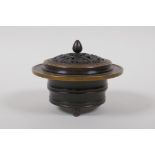 A Chinese bronze censer and pierced cover on tripod supports, with ribbed body, the cover with bat