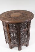 An Indian carved hardwood occasional table with circular top on octagonal folding base, 47cm high,