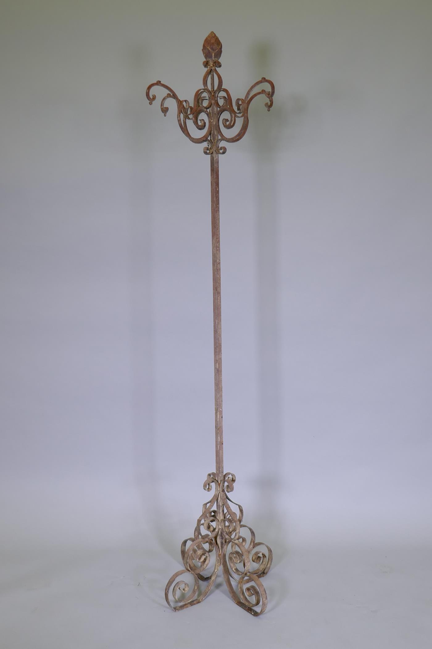 A wrought iron stand with four open work hooks and scrollwork base and artichoke finial, 160cm high