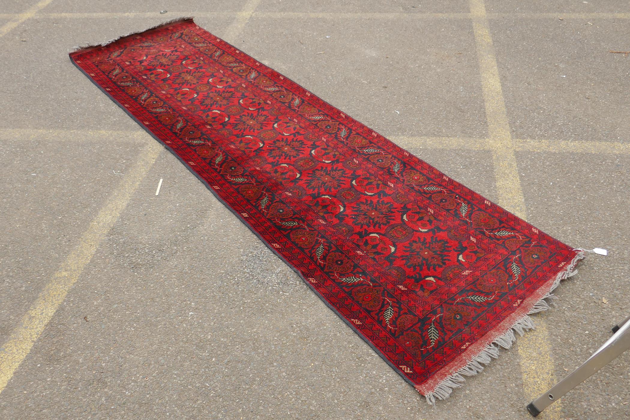 A Persian rich red ground wool runner with a floral medallion design and black borders, 33" x 116" - Image 2 of 5