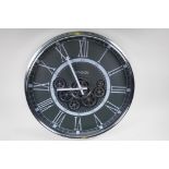A wall clock with quartz movement and separately powered open cogwork, with white Roman numerals,