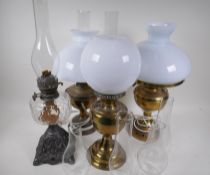 A Victorian oil lamp with cast iron base duplex burner and glass font, a brass oil lamp, two brass