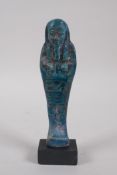 An Egyptian turquoise glazed faience shabti, mounted on a display base, 17cm high