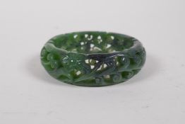 A Chinese carved and pierced green jade bangle with scrolling foliate decoration, 8cm diameter