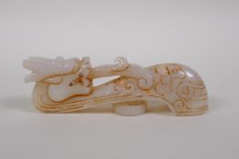 A Chinese carved white jade belt buckle with stylised dragon decoration, 10cm long