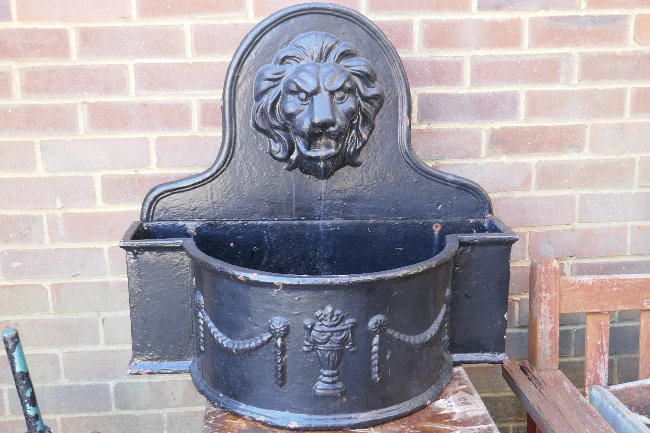 A painted cast iron wall fountain with lion's mask spout, 70 x 84cms, 65cm high