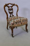 A Victorian walnut parlour chair with shaped and carved back, raised on cabriole supports