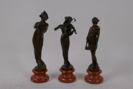 Three Art Nouveau style bronze figures, a woman blowing a kiss, playing a violin, and another