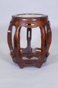 A Chinese hardwood barrel shaped stand, the top with inset porcelain panel, raised on pierced