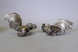 A pair of white metal figures and fighting cocks, 27cm long