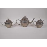 An Indian white metal three piece tea set with chased scrolling decoration, largest 29 cm long