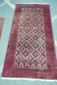 A red ground tribal rug with geometric design central pattern within five borders, 214 x 110cms