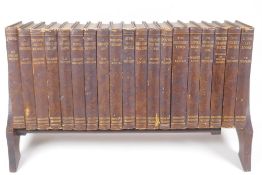 An oak book trough containing nineteen volumes 'The Minerva Editions of Modern Authors', 43cm wide