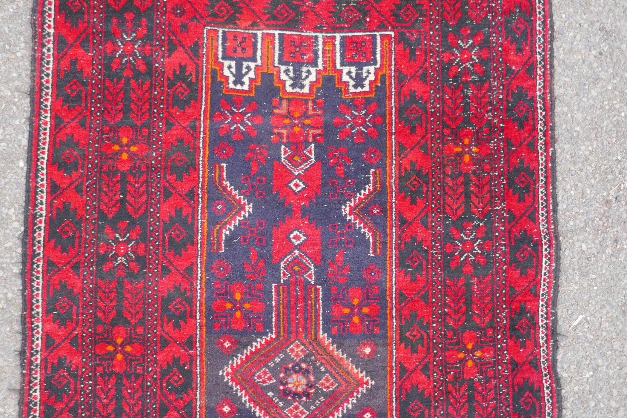 A Turkish deep red ground wool rug, with geometric designs on a central deep blue cartouche, 100 x - Image 4 of 7