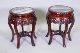 A pair of Chinese hardwood stands, with inset marble tops and carved and pierced friezes, raised