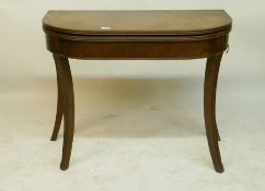 A Georgian mahogany D shaped tea table with reeded edge and cross-banded top, raised on carved sabre