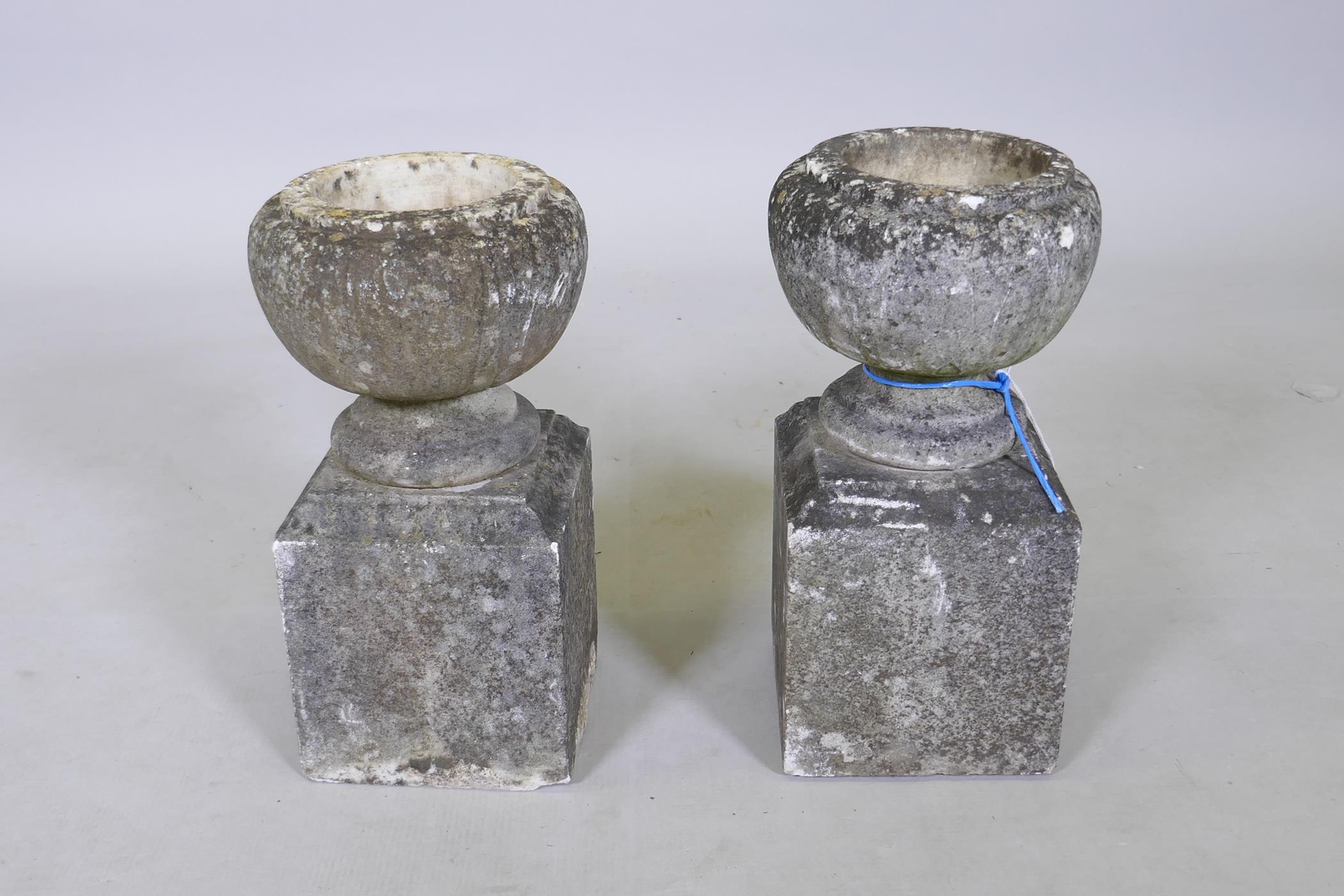 A pair of small garden urns on square pedestals, 34cm high