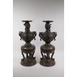 A pair of Meiji bronze stands with elephant mask handles, fo dog and dragon detail and panels