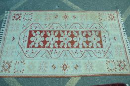 A cream ground tribal rug with central geometric decoration repeated with variations in the