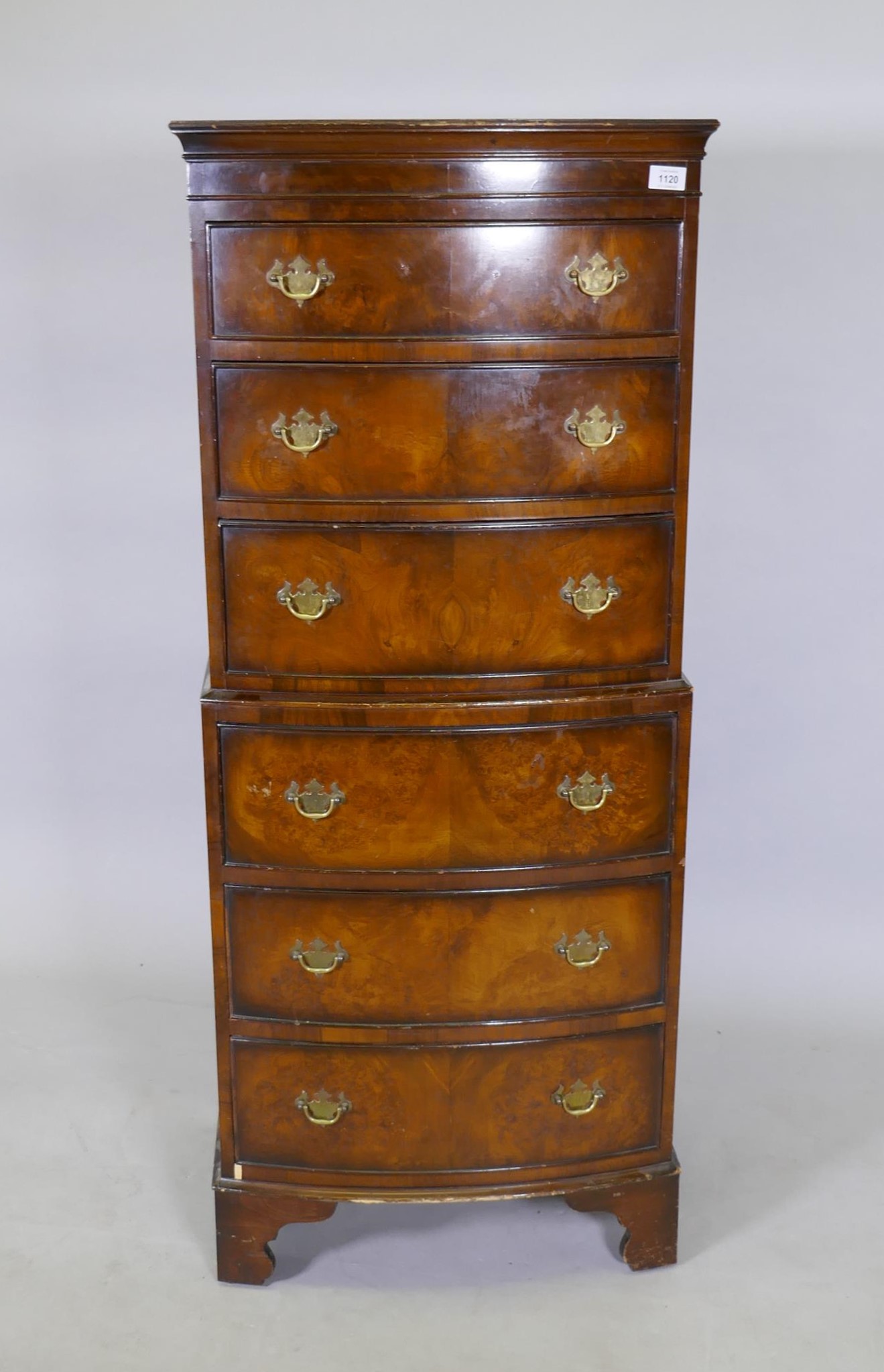 A walnut tallboy chest of six graduated drawers with brass plate handles, raised on bracket