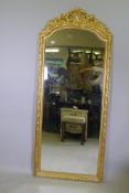 A giltwood wall mirror with carved crest and decoration, 80 x 197cms