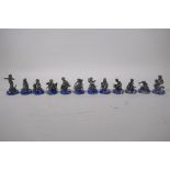 A set of twelve white metal chess pieces in the form of cherubs riding animals, on lapis lazuli