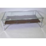 A glass top coffee table with chrome base and leatherette undertier, 120 x 70cms