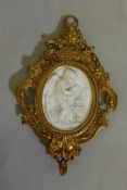 An ormolu frame with inset ceramic / glass panel, raised decoration of a cherub warming himself by a
