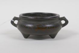A Chinese bronze two handled censer on tripod supports, impressed 9 character seal to base, 10cm