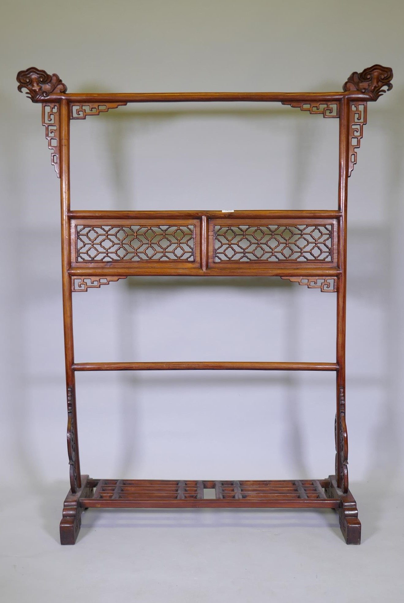 A Chinese carved wood robe rack with decorative pierced panels, 150cm high, 121cm wide