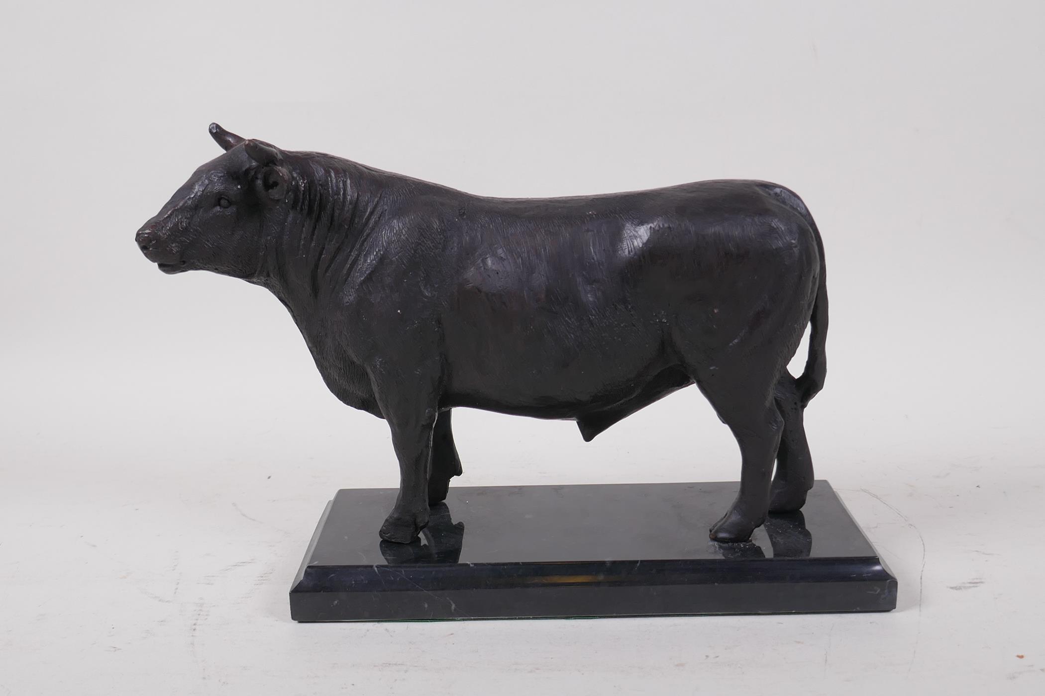 A cast bronze bull on a marble base, 26cm long