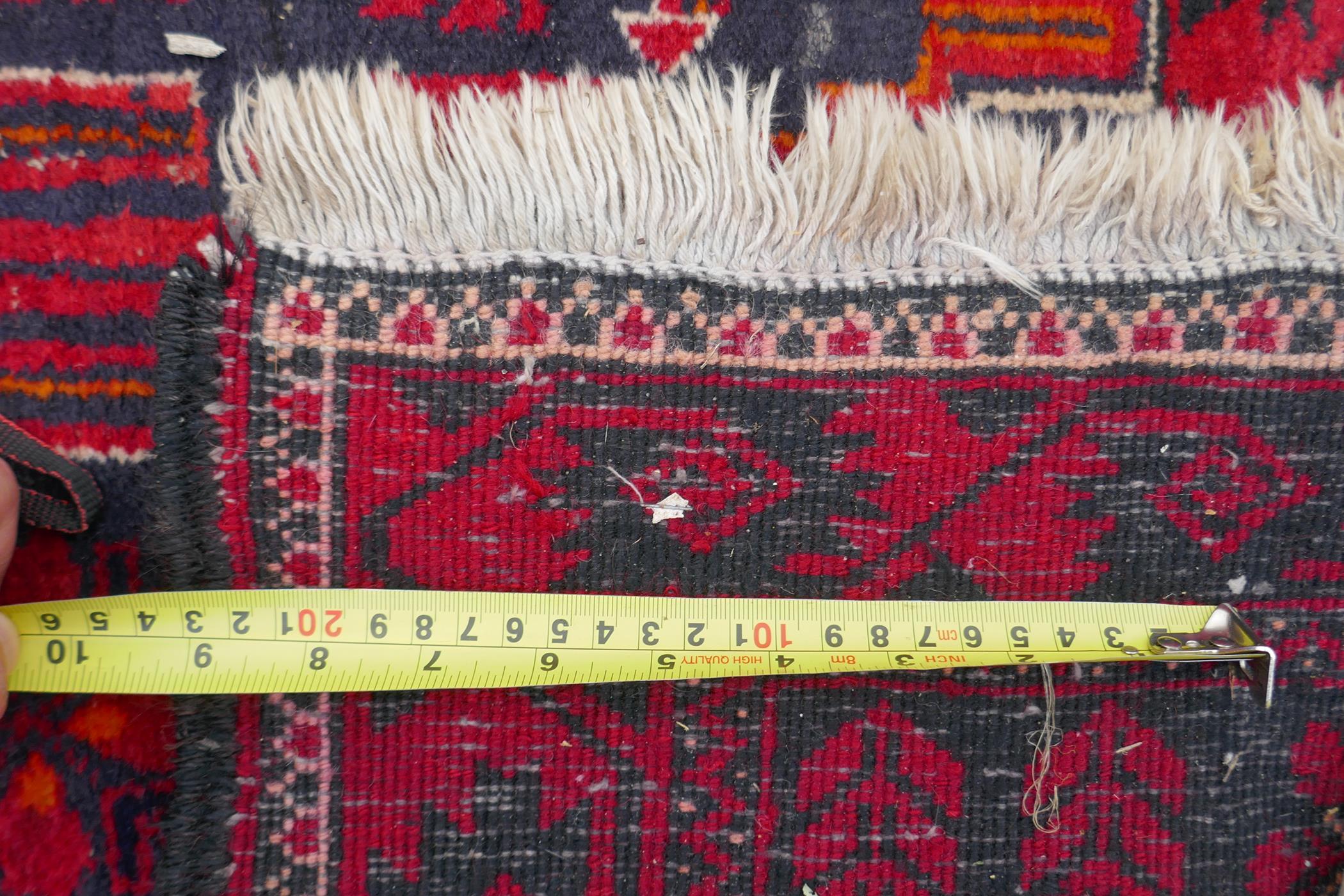 A Turkish deep red ground wool rug, with geometric designs on a central deep blue cartouche, 100 x - Image 7 of 7