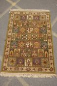A Persian olive green wool rug with a mirrored panelled design, 142 x 202cms