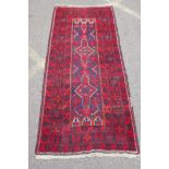 A Turkish deep red ground wool rug, with geometric designs on a central deep blue cartouche, 100 x