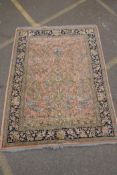 A pink ground Persian rug with a tree of life design and blue borders, 170 x 220cms