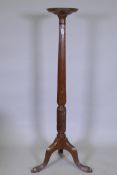 A mahogany torchere with carved and fluted column and tripod supports, 26 x 132cms