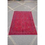 A Turkish deep red ground wool carpet with unique repeating floral geometric design, 165 x 230cms