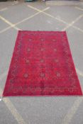A Turkish deep red ground wool carpet with unique repeating floral geometric design, 165 x 230cms