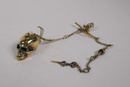 A brass Albert style watch chain with skull and bone links and details, 30cm long
