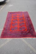 A Turkish Bokhara wool carpet with a tomato red field, 190 x 278cm