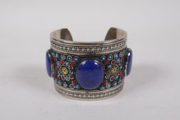 A Turkmen white metal bangle set with three lapiz lazuli cabochons, 7cm diameter