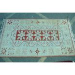 A cream ground tribal rug with central geometric decoration repeated with variations in the