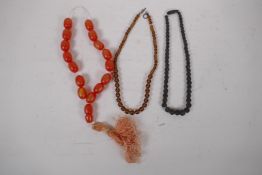 A string of amber style beads, a smoked glass bead necklace and a carved bog oak necklace, longest