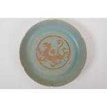 A Chinese celadon glazed porcelain dish with a petal shaped rim and chased dragon decoration, mark