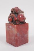 A Chinese chicken blood soapstone seal with carved dragon knop, 5cm x 5cm, 10cm high