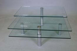 A glass coffee table with two revolving tiers, 90 x 90 x 42cms