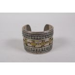 A Turkmen white metal bangle with lapiz stone ends and pressed gilt metal decoration, 7cm diameter