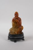 A Chinese soapstone style composition figure of Lohan with a seal to base, with display stand and