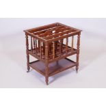 A C19th walnut canterbury with turned spindles, raised on turned supports united by an undertier