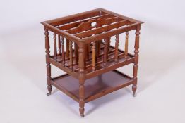 A C19th walnut canterbury with turned spindles, raised on turned supports united by an undertier